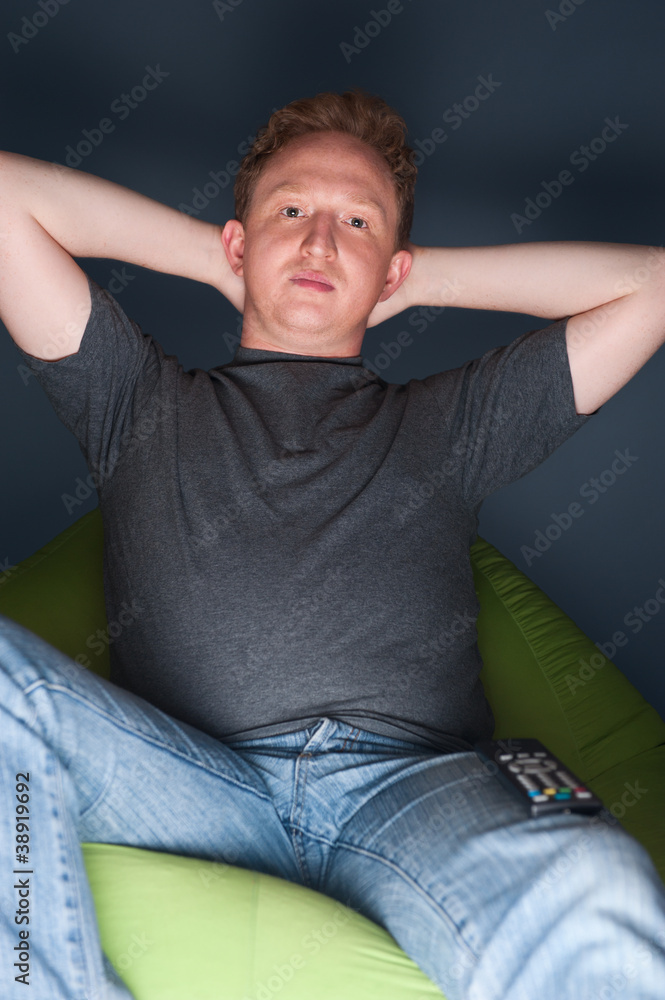 Obraz premium Portrait of young man sitting at home and watching tv