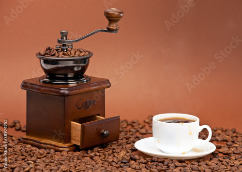 Coffee grinder and cup of coffee placed on coffee beans