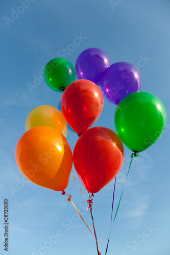Group of various colored balloons with a sky background