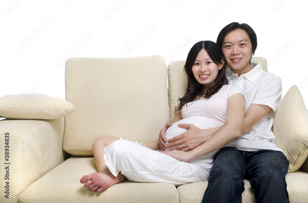 Asian couple. Husband and 8 months pregnant wife sitting on sofa Asian couple. Husband and 8 months pregnant wife sitting on sofa