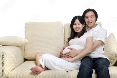 Asian couple. Husband and 8 months pregnant wife sitting on sofa