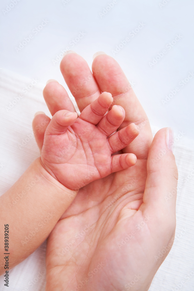 Female hand holding newborn baby's hand