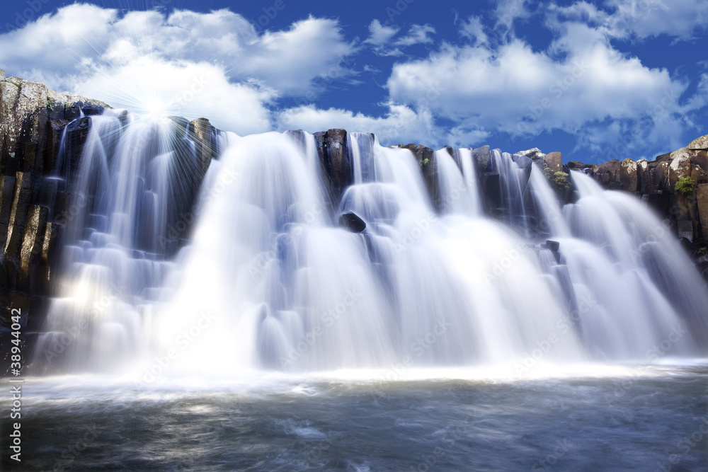 Fototapeta premium Piękny wodospad z jasnym błękitnym niebem w tle