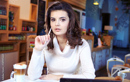A young attractive business woman sitting in a cafe with a lapto