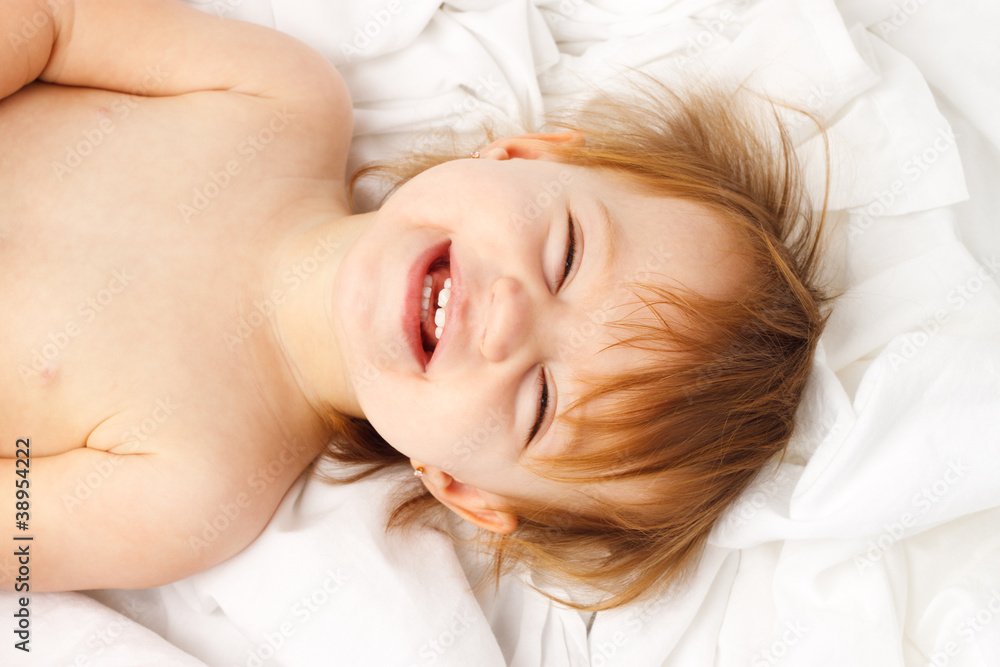 Happy child laughing and laying in white sheets Happy child laughing and laying in white sheets