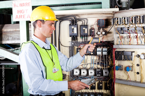electrician checking industrial machine control box temperature