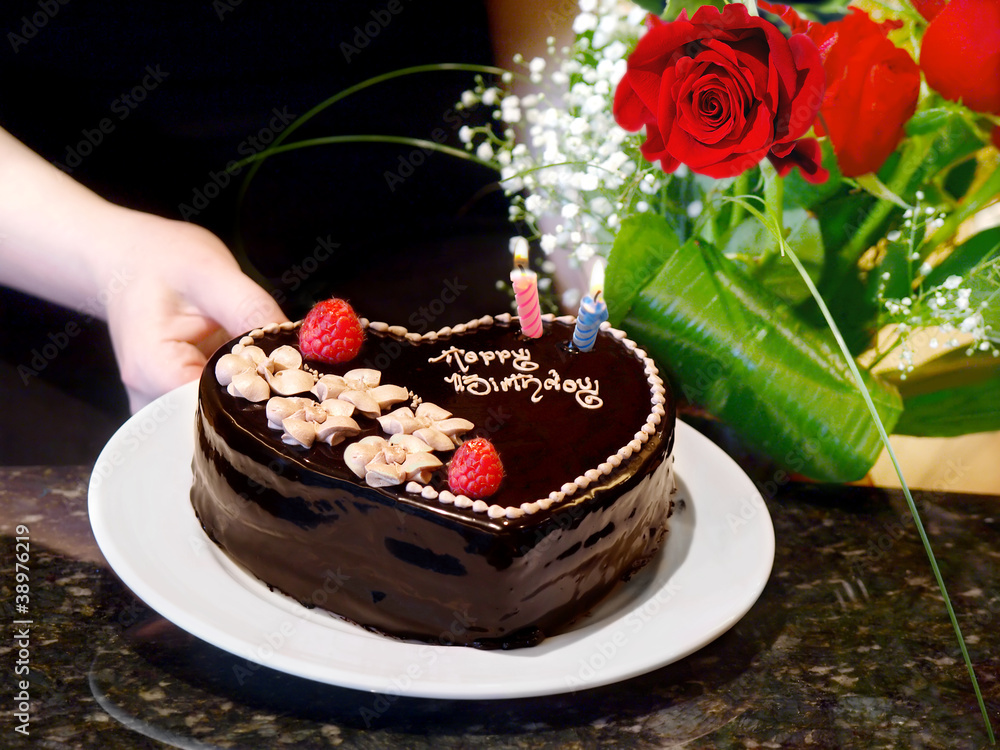 Female hands holding chocolate heart cake and roses Female hands holding chocolate heart cake and roses