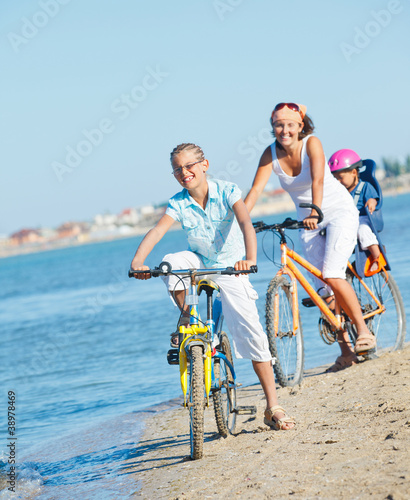 Cute girl with her mother and brother ride bikes