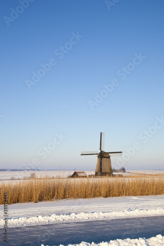 Windmill in winter time with snow, ice and blue sky