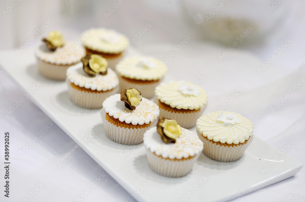 Decorated white vanilla cream cupcakes on a white plate Decorated white vanilla cream cupcakes on a white plate