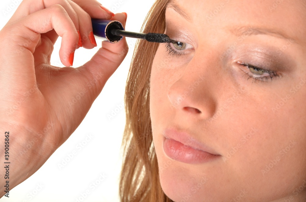 Closeup portrait of a young pretty girl applying mascara