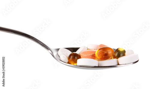 Spoon with pills isolated on white