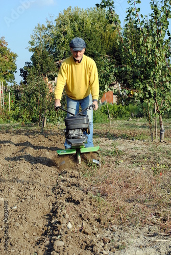 Middle age man with a rototiller in the garden