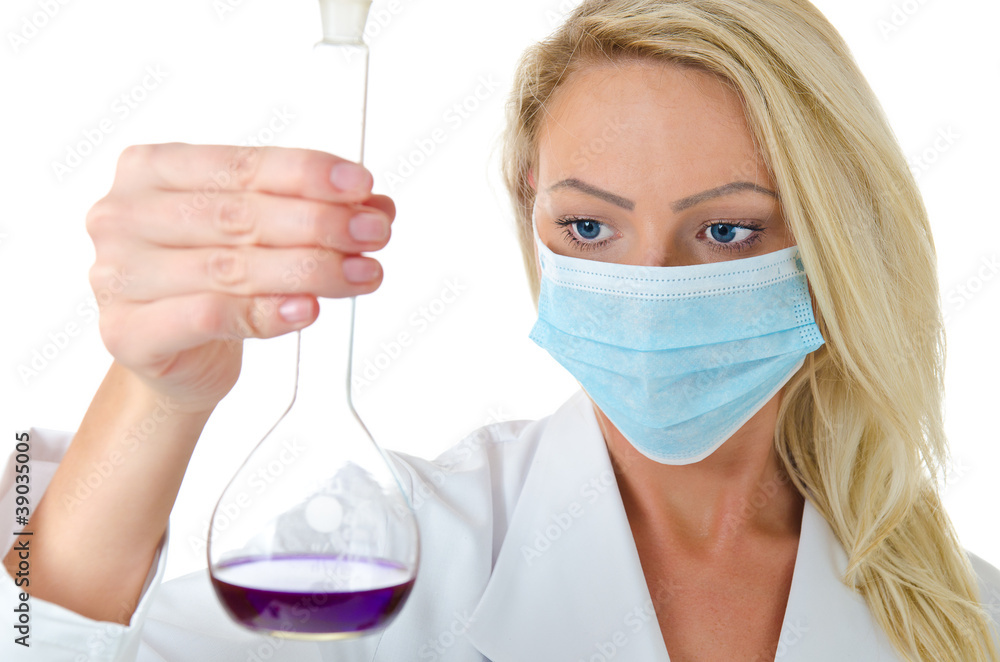 Blond female scientist in face mask mixing violet mixture Blond female scientist in face mask mixing violet mixture