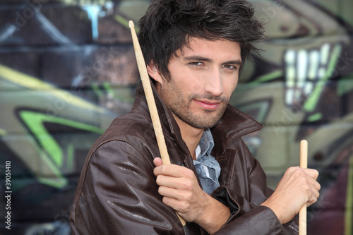 Drummer standing in front of graffiti photo