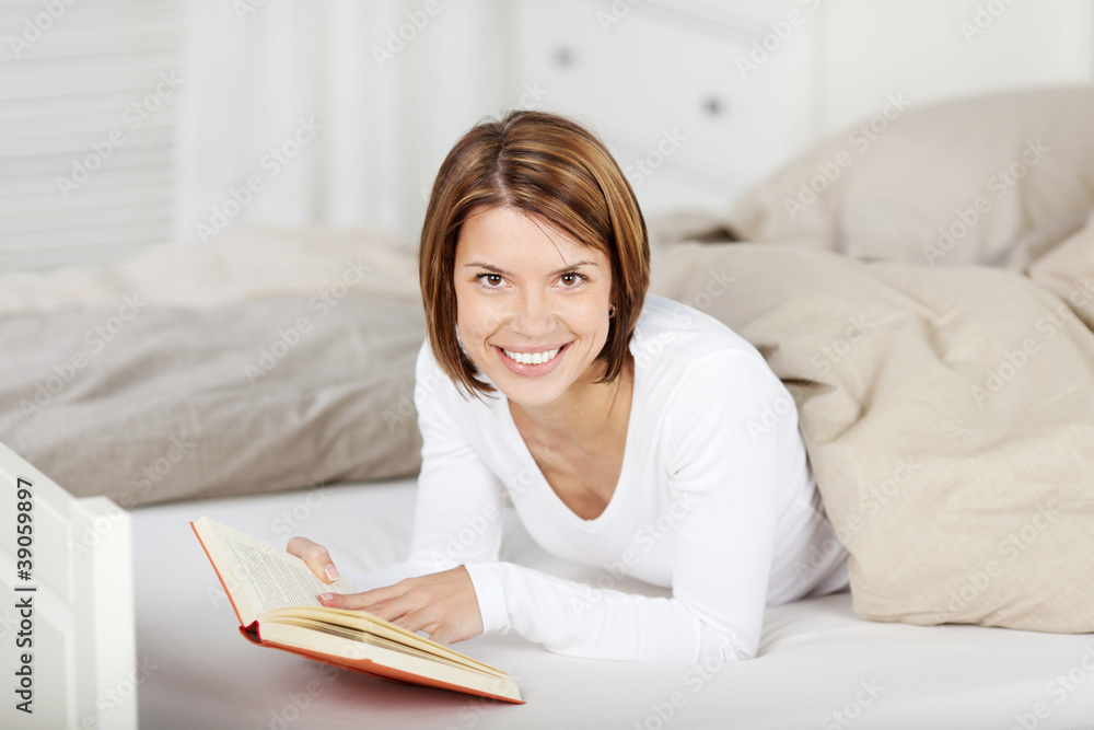 lächelnde frau mit einem buch im bett lächelnde frau mit einem buch im bett