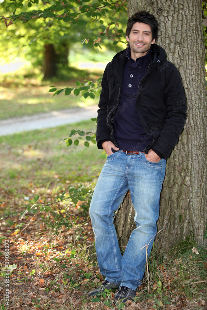 young man near a tree in autumn young man near a tree in autumn