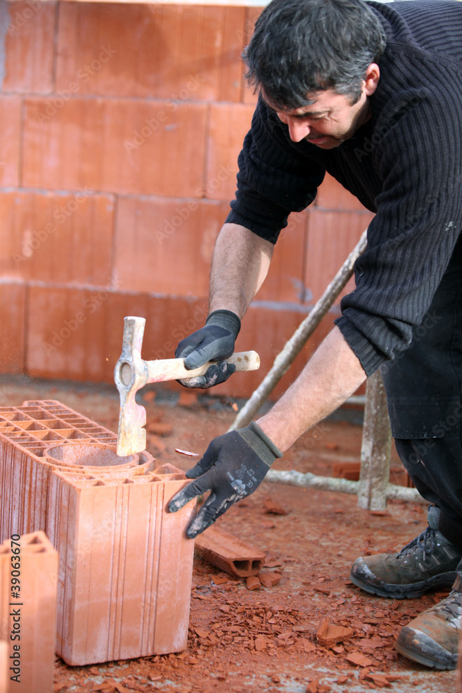 Builder hammering a brick