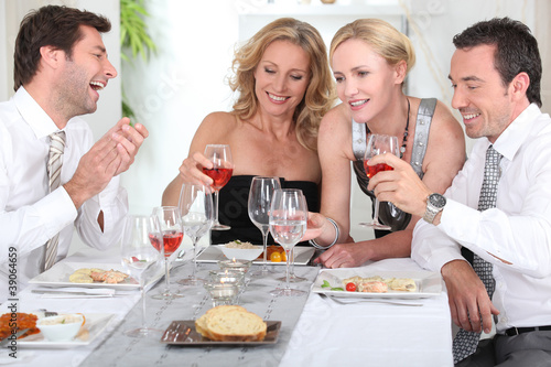 Four joyful people at the start of a posh dinner.