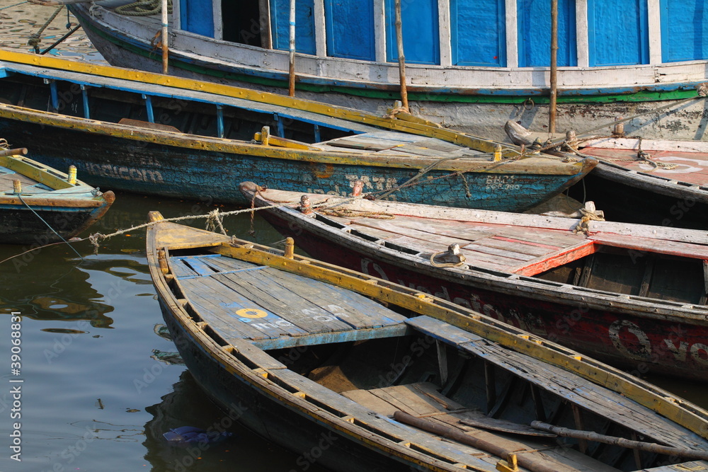 Colorful boats on brown waters of Ganges river, Varanasi, India
