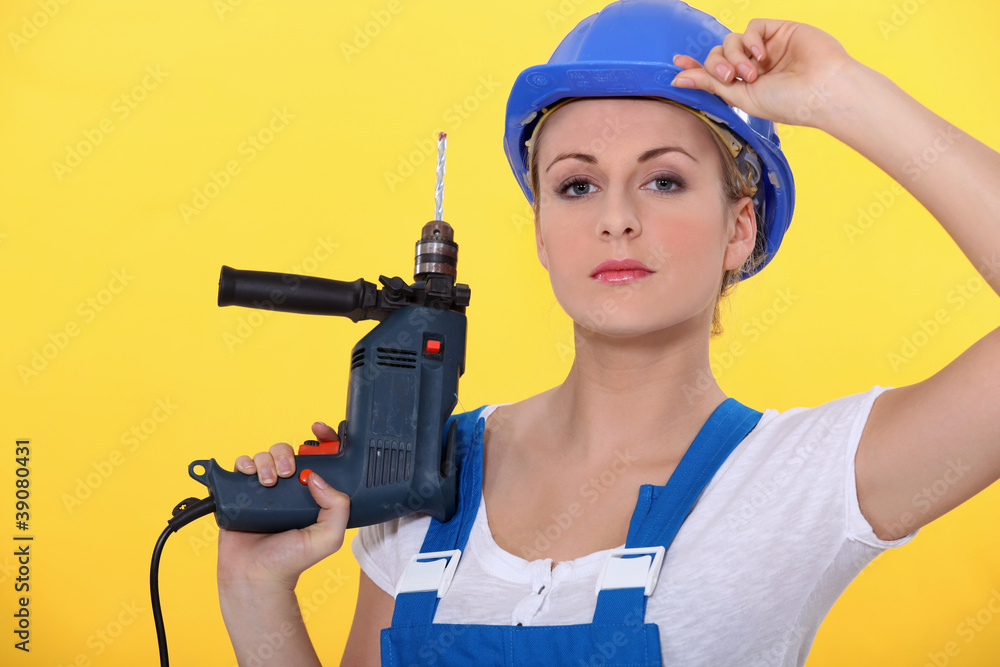 woman wearing an overall posing with a drill woman wearing an overall posing with a drill