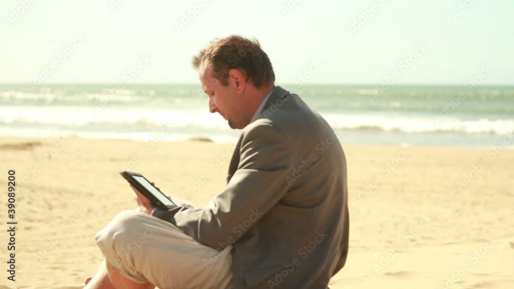 Businessman working on tablet computer on beach by the sea Businessman working on tablet computer on beach by the sea
