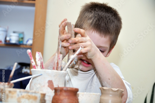 child  boy shaping clay in pottery studio photo