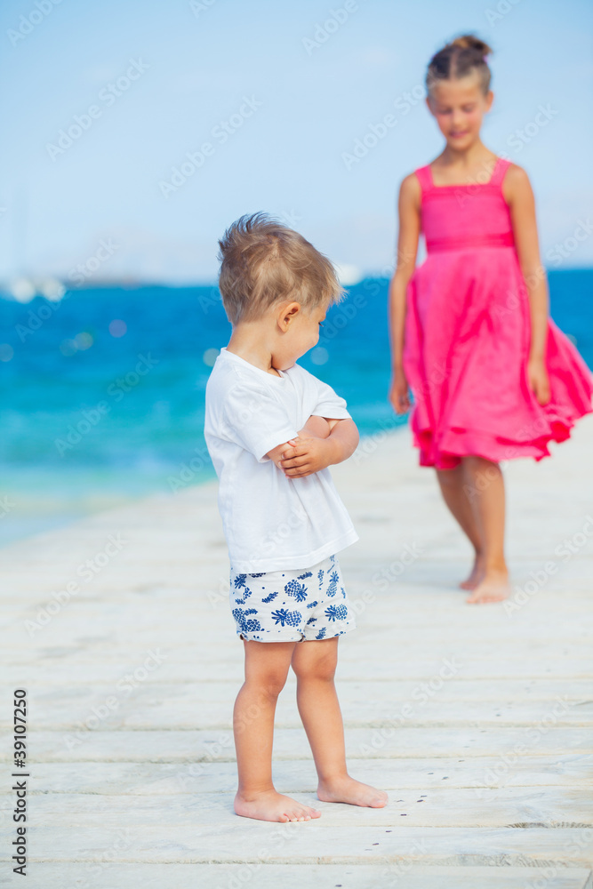 Boy with his sister walking on jetty Boy with his sister walking on jetty