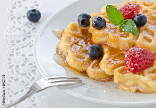 Stack of waffles with fruit and honey.