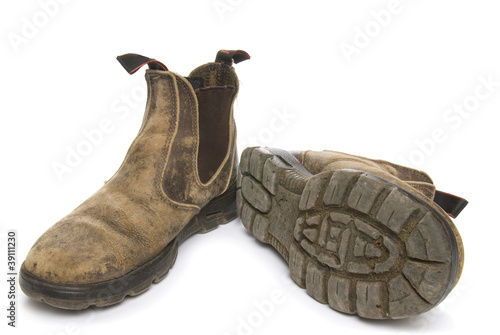 Old pair of dirty working boots on white background photo