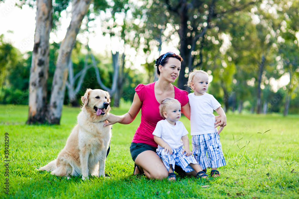 Mother and her two sons in the park with a golden retriever