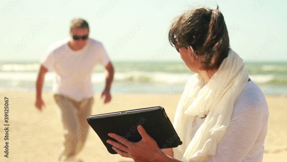 Happy young couple chatting on tablet computer on the beach Happy young couple chatting on tablet computer on the beach