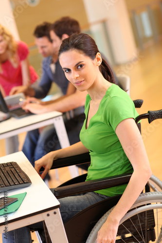 Young woman in wheelchair working in office © goodluz