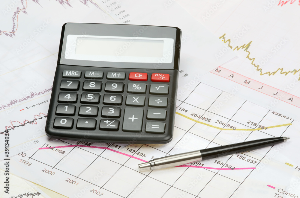 calculator and pen on a financial charts calculator and pen on a financial charts
