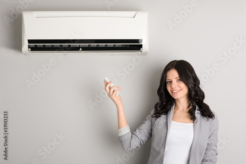 girl holding a remote control air conditioner © Stanislav Komogorov