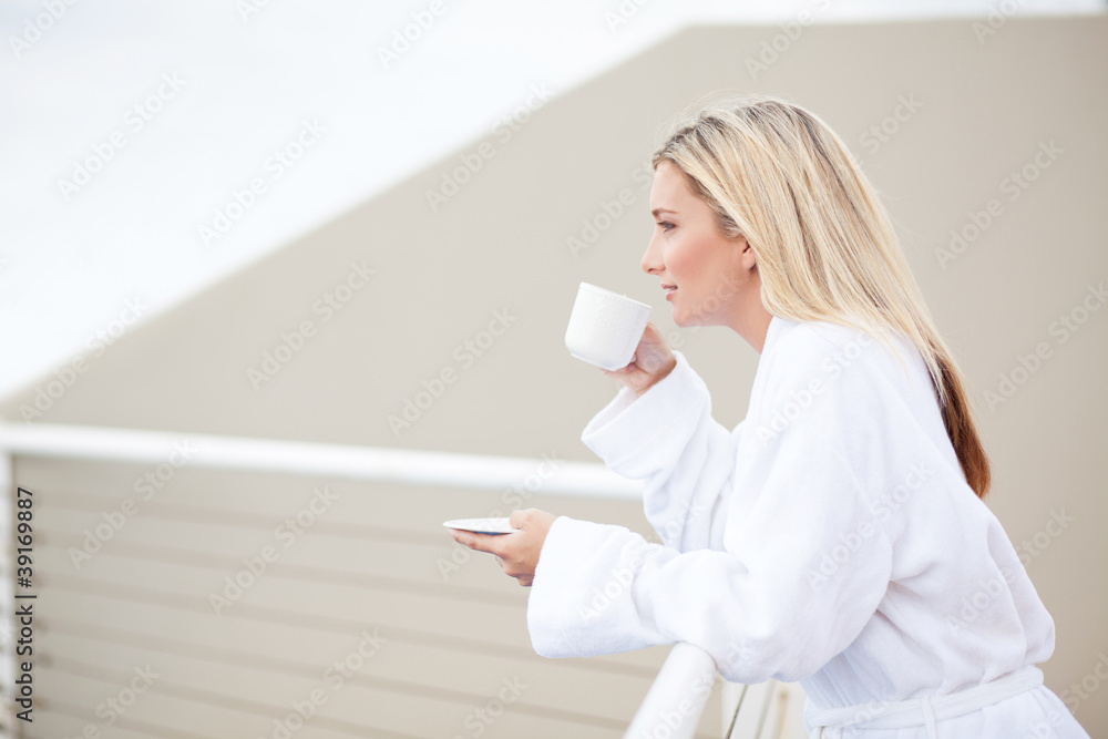young woman in bathrobe drinking coffee on balcony young woman in bathrobe drinking coffee on balcony