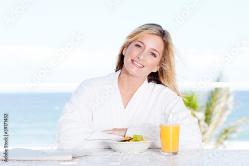 cheerful young woman at breakfast table with sea view