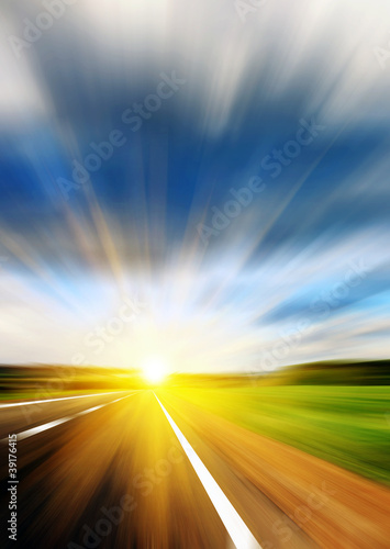 Blurred road and blue blurred sky with a shining sun