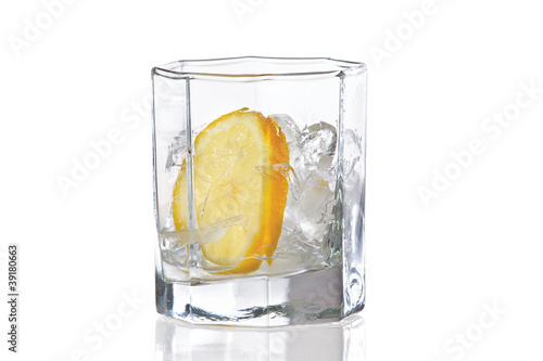 Glass with ice and slice of fresh lemon on a white background