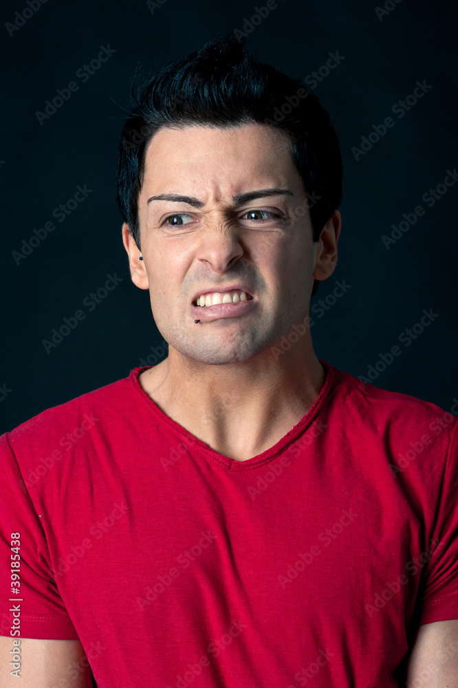 Man portrait with angry expression on dark background.