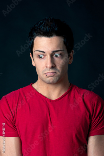 Man portrait with doubtful expression on dark background.