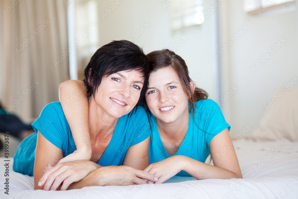 middle aged mother and teen daughter lying on bed relaxing middle aged mother and teen daughter lying on bed relaxing