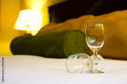 Two empty wine glasses on bed