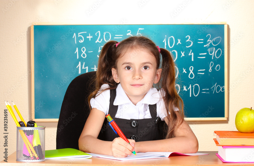 little schoolchild in classroom near blackboard