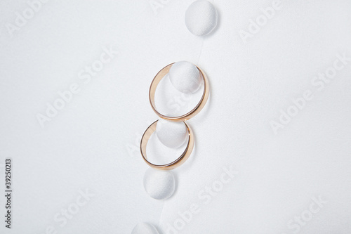 Two wedding rings with white button in the background.