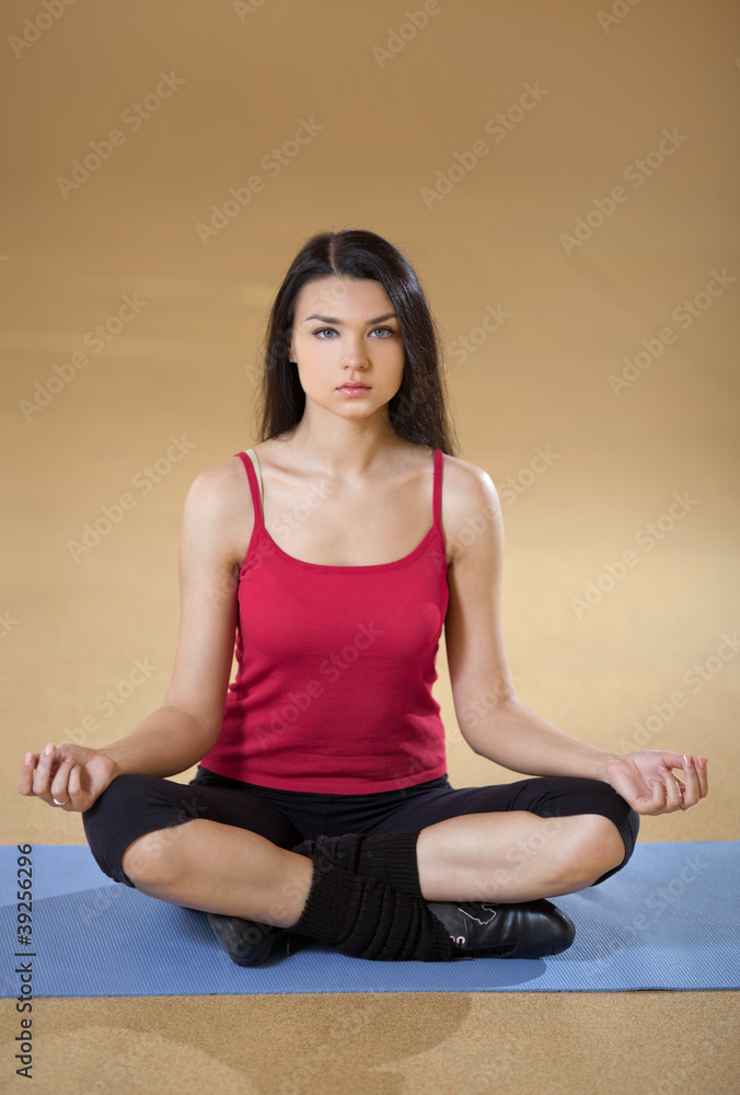 Portrait of healthy young woman practicing yoga on exercising ma