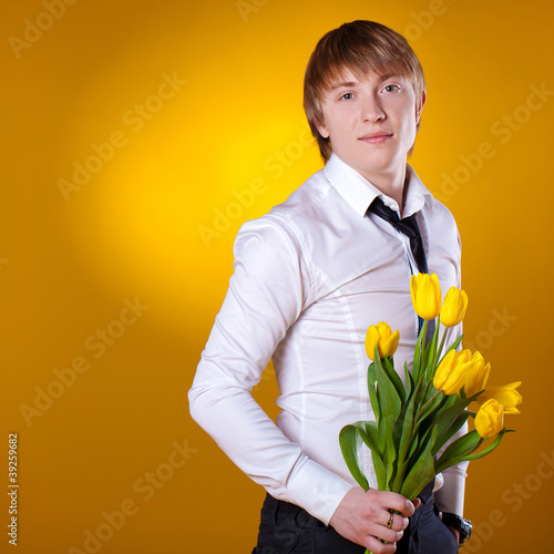 Foto Elegant man holding flowers on yellow