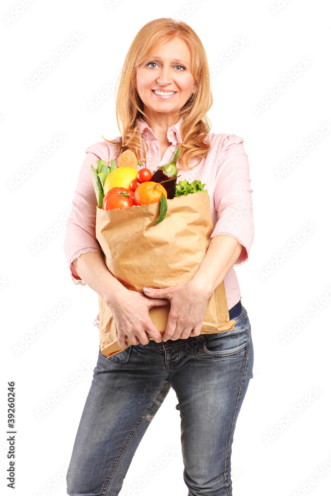 A smiling woman holding a paper bag full of groceries A smiling woman holding a paper bag full of groceries