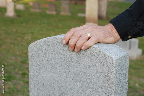 Man's hand resting on headstone