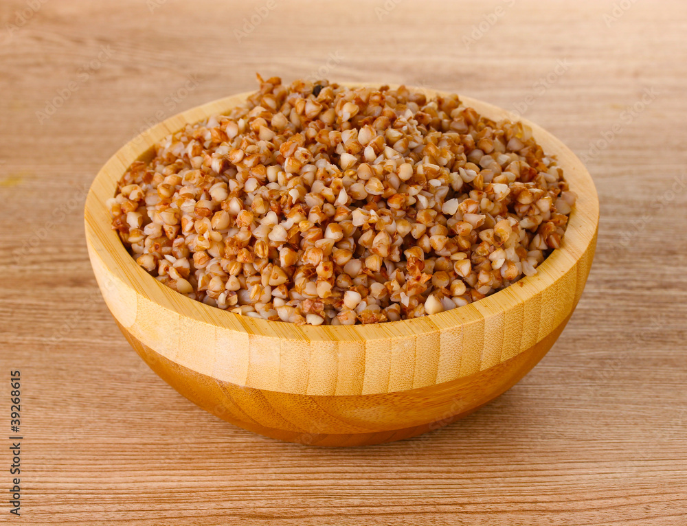 Boiled buckwheat in a wooden bowl on wooden background Boiled buckwheat in a wooden bowl on wooden background